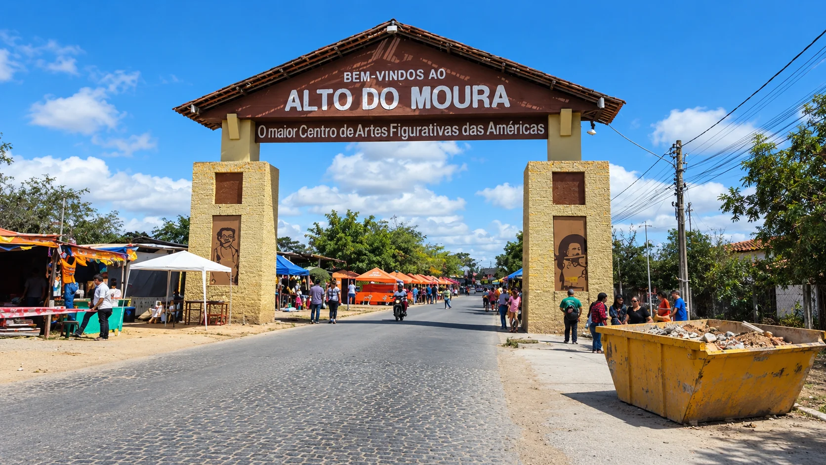 Caçamba amarela cheia de entulho na entrada do Alto do Moura, com a feira de artesanato e visitantes ao fundo